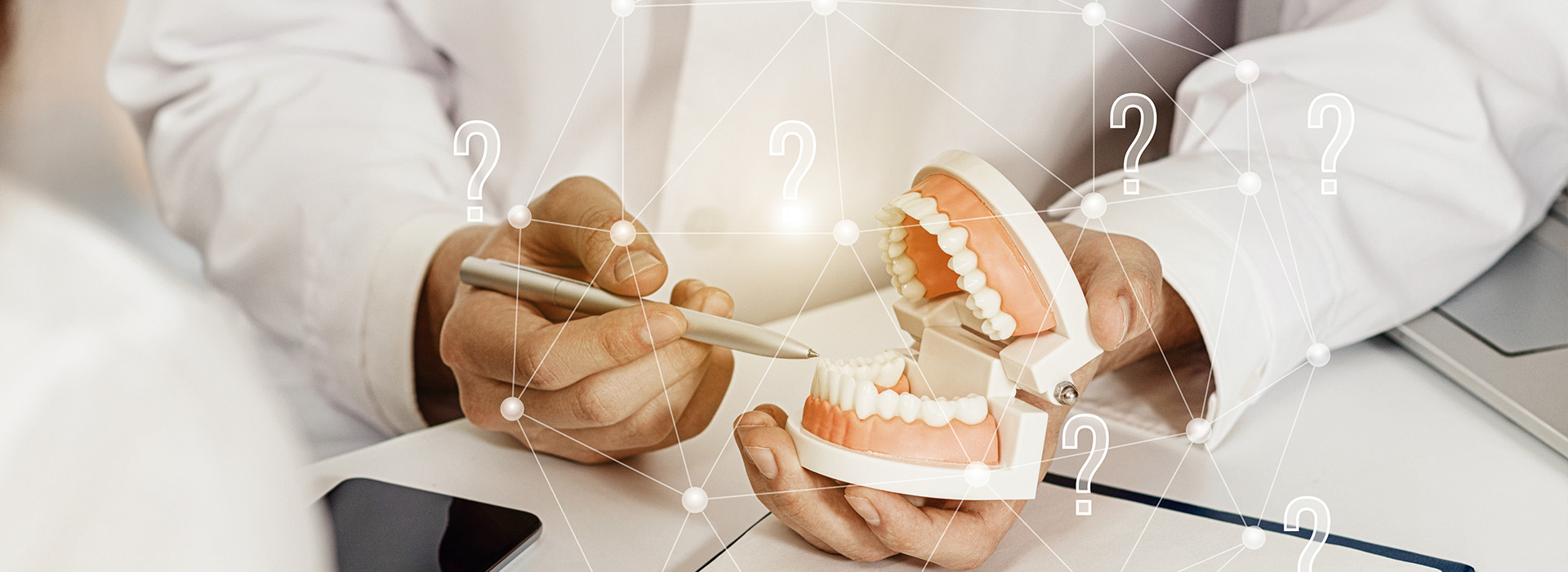 A dental professional holding a set of teeth with various options displayed, accompanied by a digital interface showing possible tooth replacement solutions.