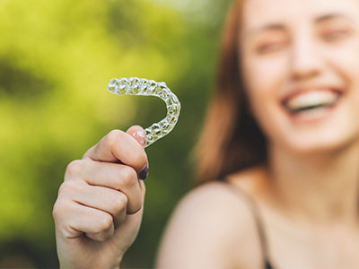 The image shows a person holding up a toothbrush with a smile, likely to promote oral hygiene.