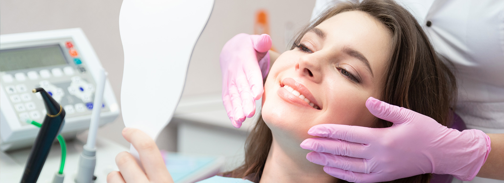 A woman is receiving dental care, with a dentist performing a procedure on her teeth while she sits in a chair.