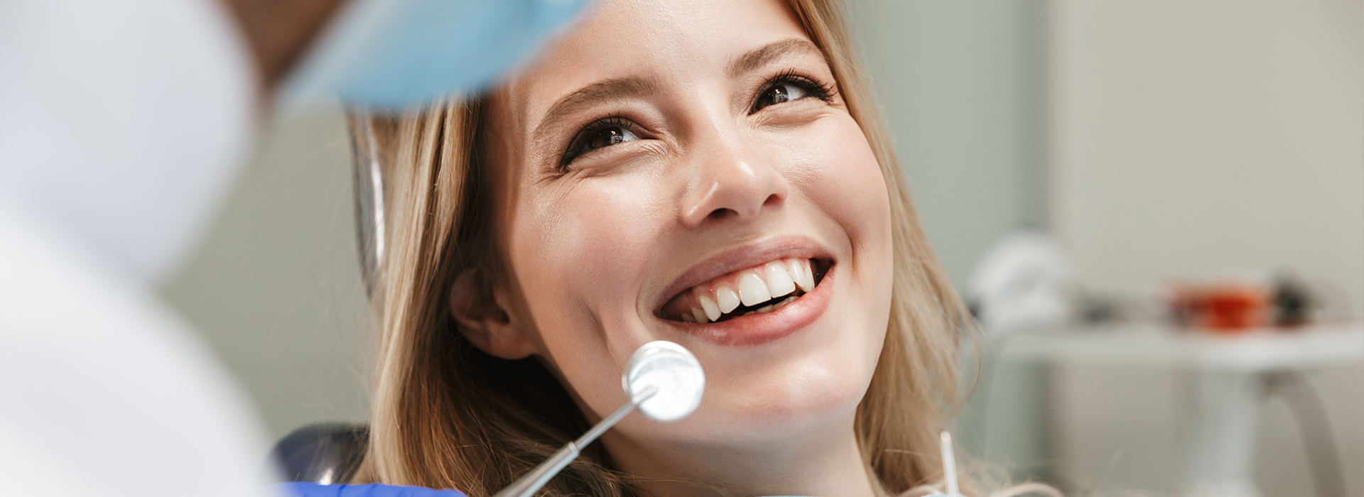 A smiling woman receiving dental care from a professional in a clinical setting.