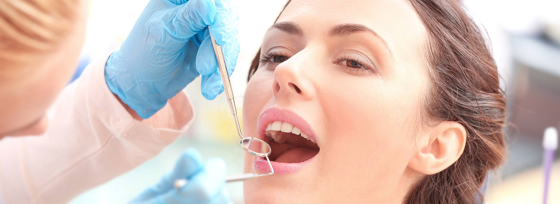 A woman receiving dental care, with a dentist performing a procedure using a drill and a dental dam.