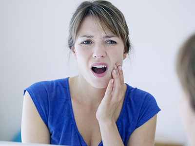 A woman with an open mouth, possibly expressing surprise or concern, is shown in a close-up with a blurred background.