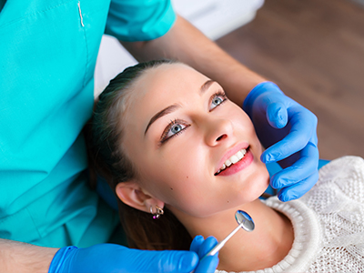 A dental hygienist is performing a teeth cleaning procedure on a woman s mouth.