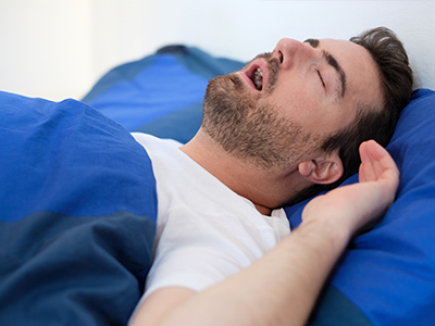 A man sleeping in bed, with his head resting on a pillow.